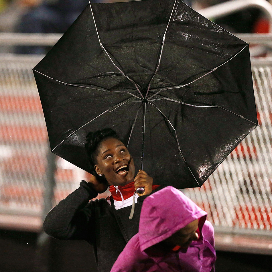 Iowa City High student Lyric Davenport reacts as her umbrella blows in the wind during the Little Hawks game against Iowa City West in a class 4A high school football game at City High School in Iowa City on Friday, Sept. 18, 2015. (Adam Wesley/The Gazette)