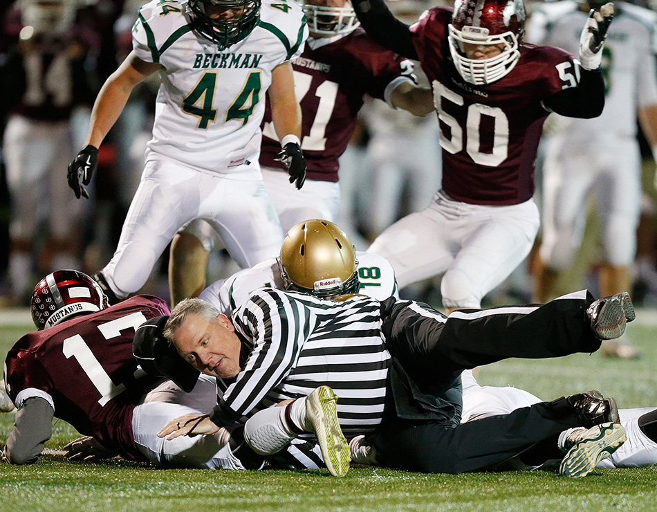 A referee gets tripped up after a fumble during Mount Vernon's game against Dyersville Beckman in a 1st round class 2A high school football playoff game at Ash Park Stadium at Cornell College in Mount Vernon on Wednesday, Oct. 28, 2015. (Adam Wesley/The Gazette)